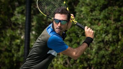 Four pairs of tennis sunglasses on a hard court surface